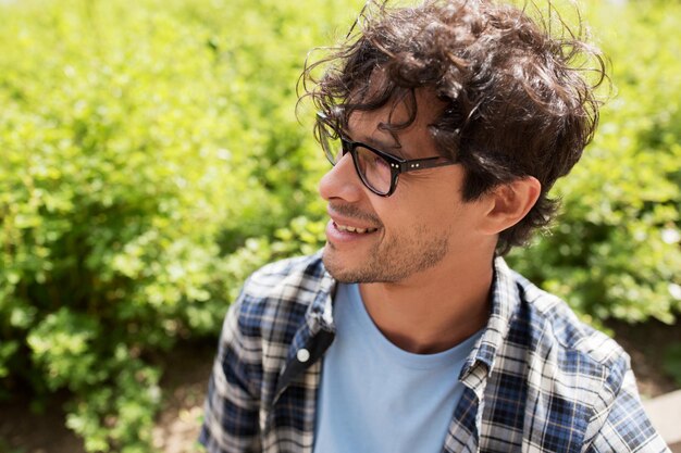 Lifestyle, emotion, expression and people concept - close up of happy smiling man in eyeglasses outdoors