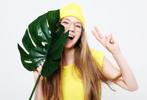 Foto emozione di stile di vita e concetto di persone bella donna sorridente dietro una grande foglia