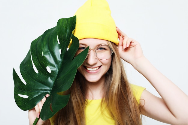 Lifestyle, emotion and people concept: Smiling woman behind big leaf