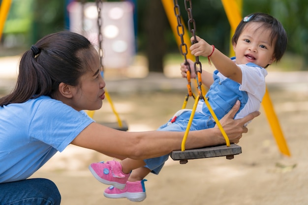 Stile di vita famiglia, felice mamma e figlia godendo il tempo nel parco giochi nel parco