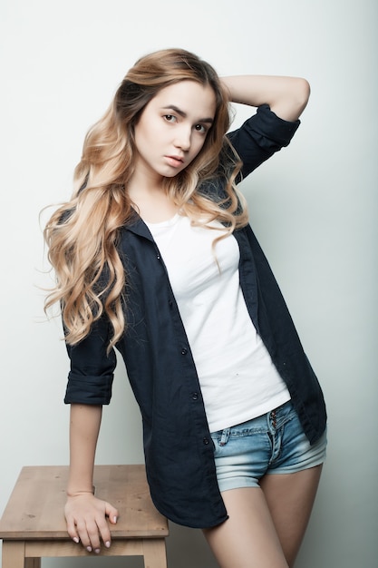 Lifestyle, fashion and people concept: beautiful curly woman wearing casual clothes, posing on white wall