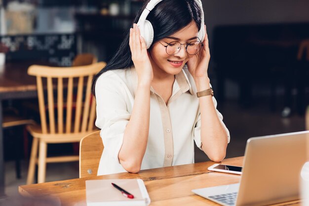 ライフ スタイル フリーランスの働く女性とラップトップ コンピューター彼コーヒー カフェ ショップで音楽ラジオを聞いて