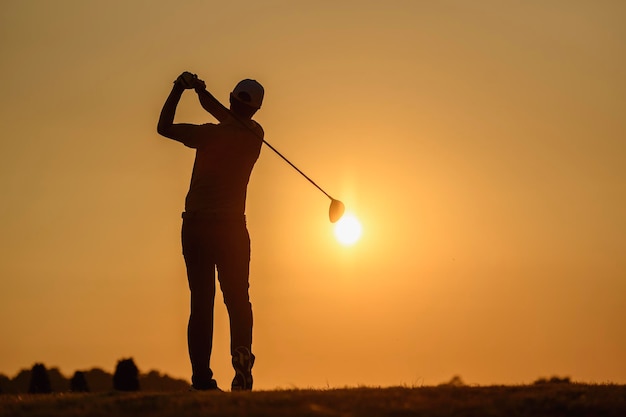 Foto lifestyle, golf, activiteit, outdoor, sport, golfer concept een man veegt golf op het zand op een golfbaan bij zonsondergang in de zomer. sport levensstijl concept.
