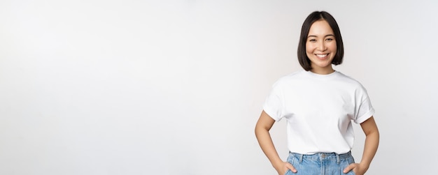 Lifestyle Happy modern asian girl smiling and looking happy at camera posing in white tshirt and jeans studio background