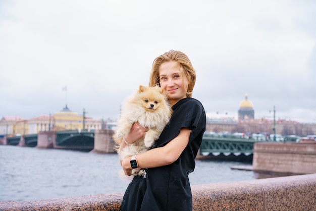 Lifestyle image of happy attractive young woman in black leather jacket walking on the river promena...