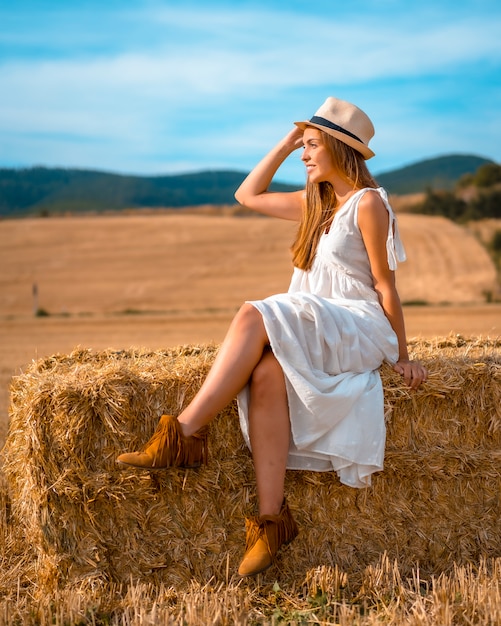 Lifestyle, jonge blonde blonde boer met witte jurk en een witte hoed op een zomermiddag