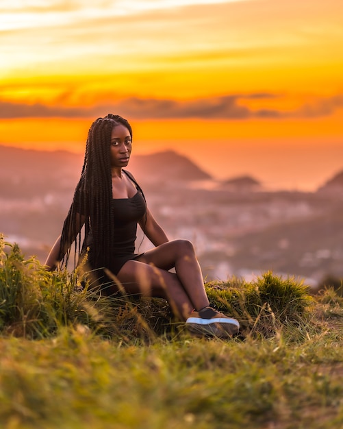 Lifestyle Latina girl with black skin with beautiful long braids in her hair wearing a tight black short dress