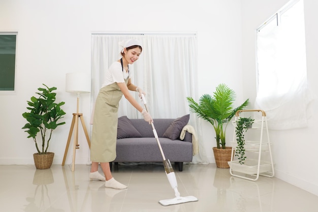 Lifestyle in living room concept Young Asian woman cleaning the floor with vacuum cleaner