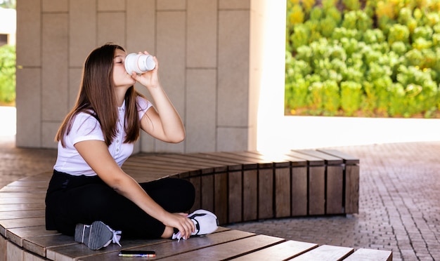 ライフスタイルと現代の人々のコンセプト-一杯のコーヒーと市夏の通りに電話で10代の少女