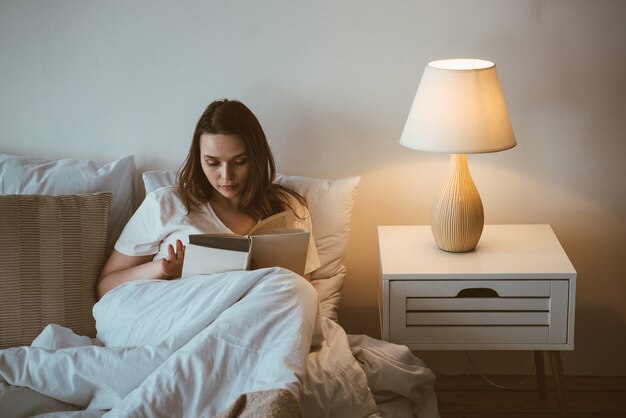 Lifestyle-momenten van een jonge vrouw thuis. Vrouw leest voor het slapen gaan