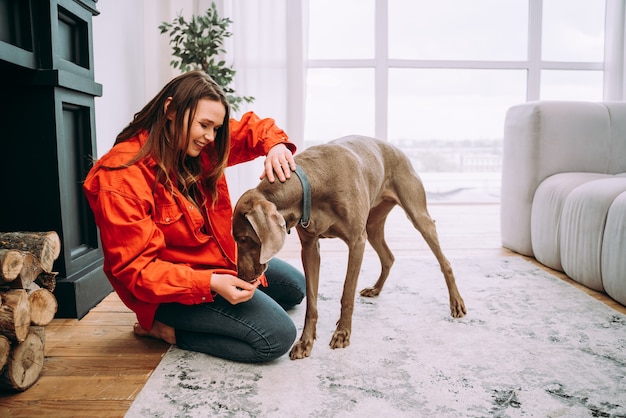 Lifestyle-momenten van een jonge vrouw thuis. Vrouw speelt met haar hond in de woonkamer