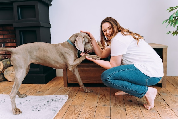 Lifestyle-momenten van een jonge vrouw thuis. Vrouw speelt met haar hond in de woonkamer