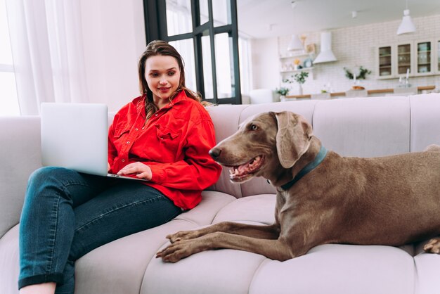 Lifestyle-momenten van een jonge vrouw thuis. Vrouw speelt met haar hond in de woonkamer