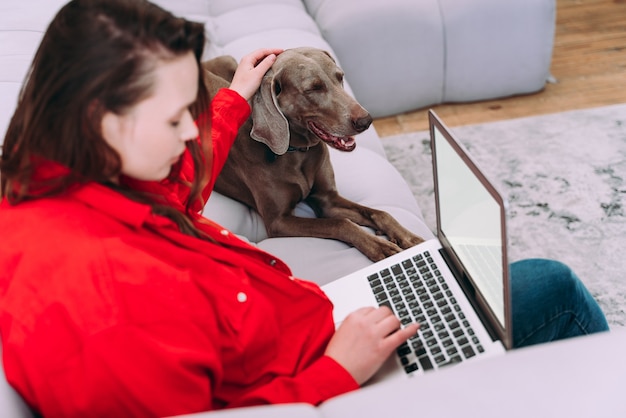 Lifestyle-momenten van een jonge vrouw thuis. Vrouw speelt met haar hond in de woonkamer