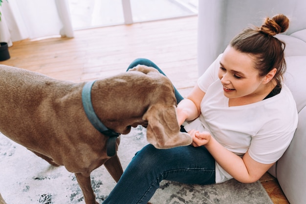 Lifestyle moments of a young woman at home. Woman playing with her dog in the living room