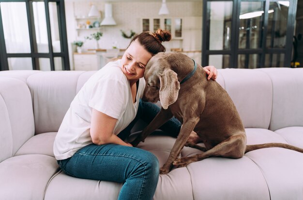 自宅で若い女性のライフスタイルの瞬間。居間で犬と遊ぶ女性