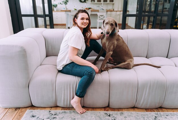 自宅で若い女性のライフスタイルの瞬間。居間で犬と遊ぶ女性