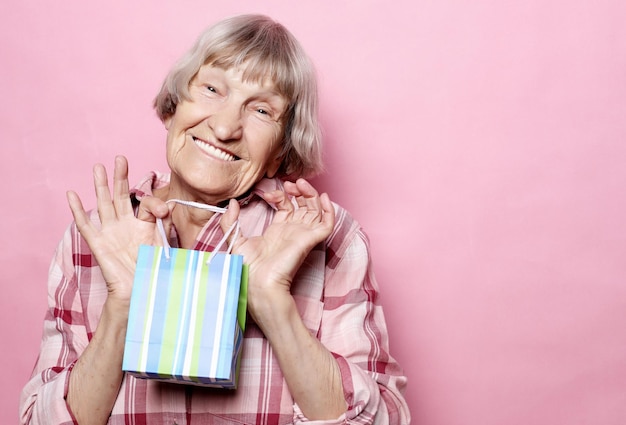 라이프 스타일과 사람들의 개념 분홍색 배경 위에 쇼핑백을 든 행복한 노인 여성