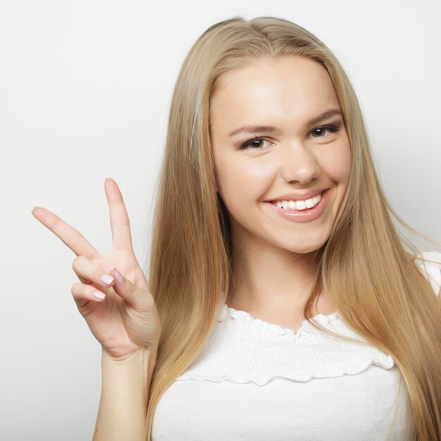 Lifestyle and people concept: lovely woman showing victory or peace sign