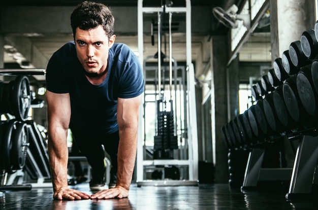 lifestyle and people concept - man exercising work out and flexing muscles in gym 