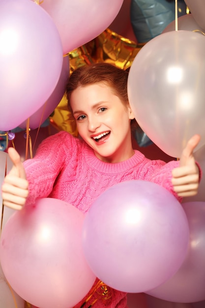 Lifestyle and people concept Portrait of happy smiling young woman showing okay gesture over background of balloons