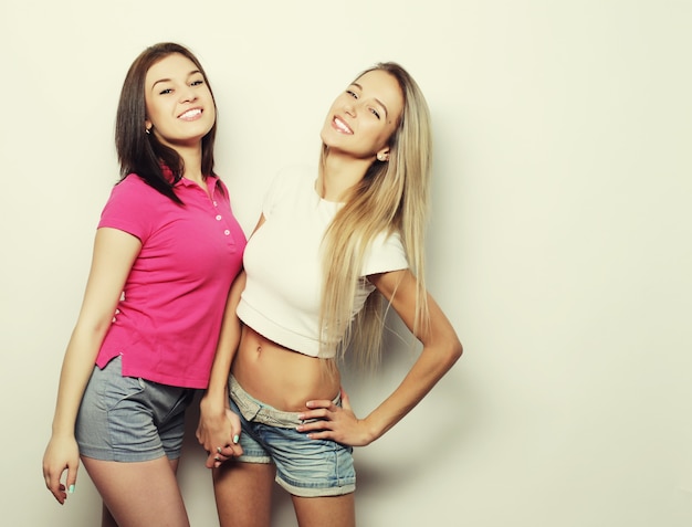 Lifestyle and people concept: Two young girl friends standing together and having fun. Looking at camera.