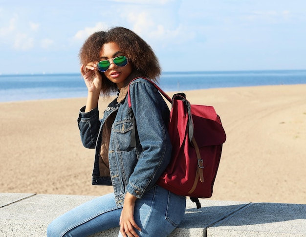 Lifestyle and people concept Young black woman with backpack on the beach