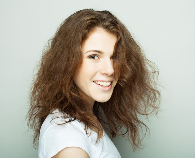 Lifestyle and people concept: Young casual woman portrait. Clean face, curly hair. Happy girl close up face.