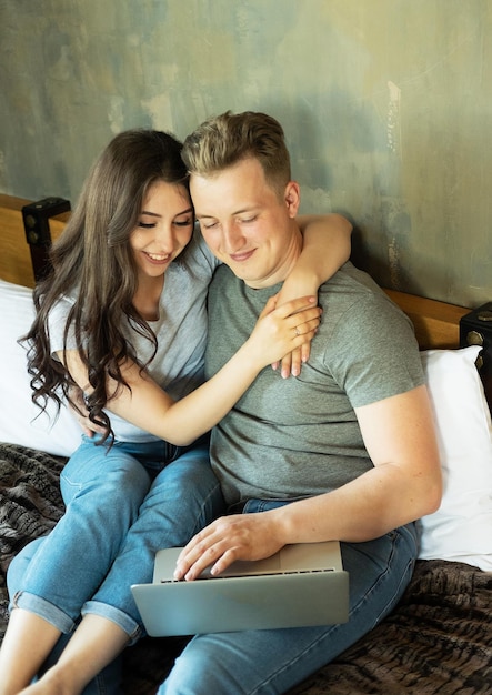 Lifestyle and people concept Young married couple lying on bed at home and using laptop