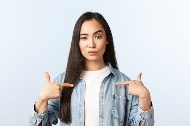 Stile di vita, emozioni delle persone e concetto di bellezza. ragazza asiatica sfacciata e sicura che si indica, promuove servizi personali come freelance durante la pandemia di coronavirus, esibizionismo o vanto