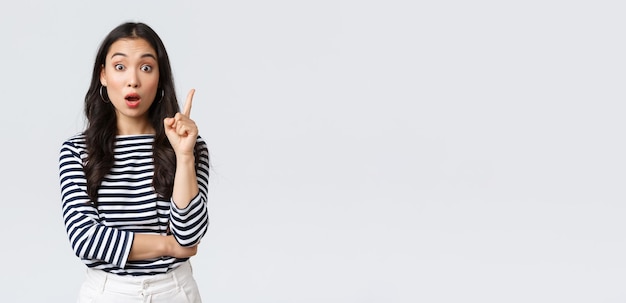 Lifestyle people emotions and casual concept Excited smart and creative asian female coworker have suggestion add idea raising index finger to say thought or plan standing white background