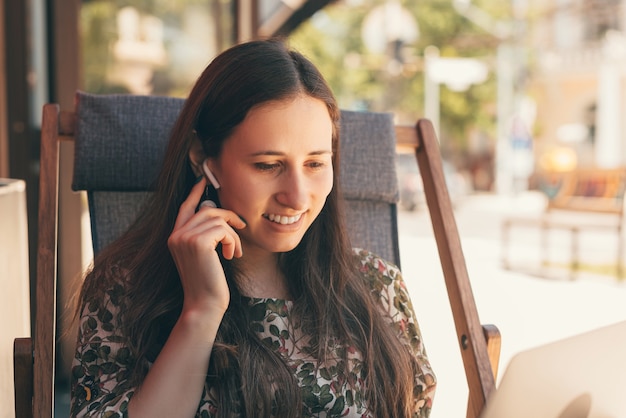 Lifestyle photo of a young woman sitting on chair connecting her ear-pods.