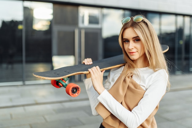 Lifestyle portrait of a beautiful girl with a skateboard.