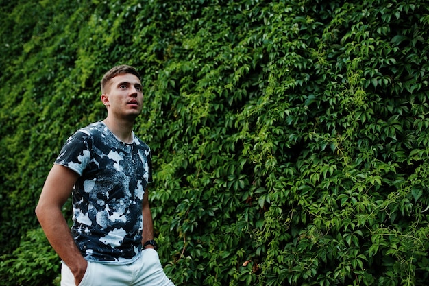 Lifestyle portrait of handsome man posing against greenery wall