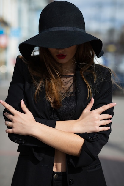 Lifestyle portrait of mysterious brunette lady wears wide brimmed hat and lingerie posing at the city