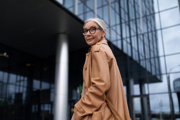 Photo lifestyle portrait of a senior woman against the backdrop of an office building in half a turn