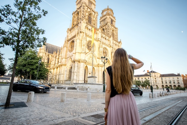 Lifestyle portrait of a woman walking near the famous cathedral during the sunset in Orleans, France