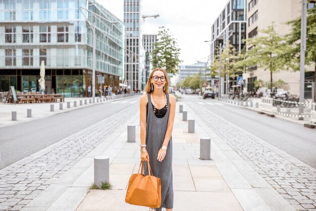 Lifestyle portrait of a younf stylish businesswoman walking on the street in modern office district of hamburg city, germany