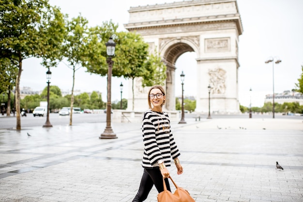 Ritratto di stile di vita di una giovane donna d'affari alla moda che cammina all'aperto vicino al famoso arco trionfale di parigi