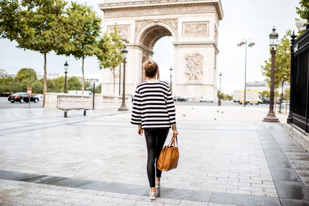 Ritratto di stile di vita di una giovane donna d'affari alla moda che cammina all'aperto vicino al famoso arco trionfale di parigi