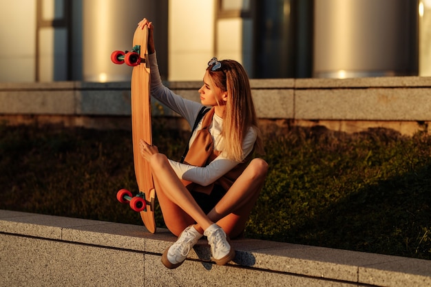 Lifestyle portrait of young woman with longboard. High quality photo