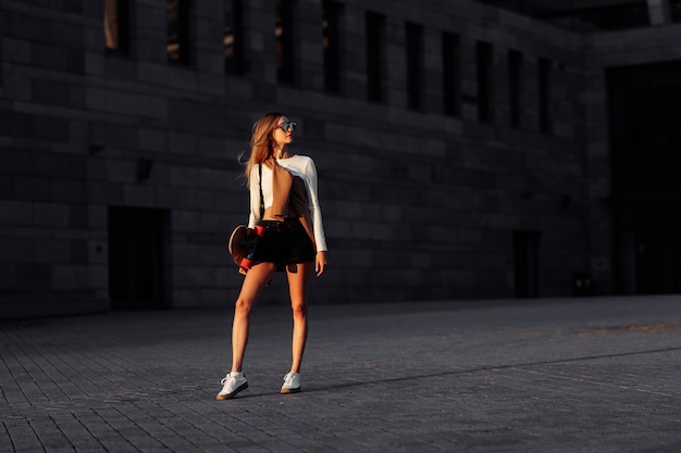 Lifestyle portrait of young woman with longboard. High quality photo