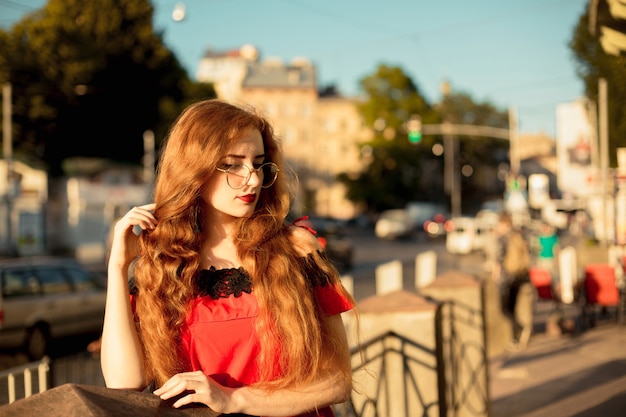 Lifestyle portret van cool roodharige meisje met sproeten. Model met lang krullend haar dat een bril draagt. .Ruimte voor tekst