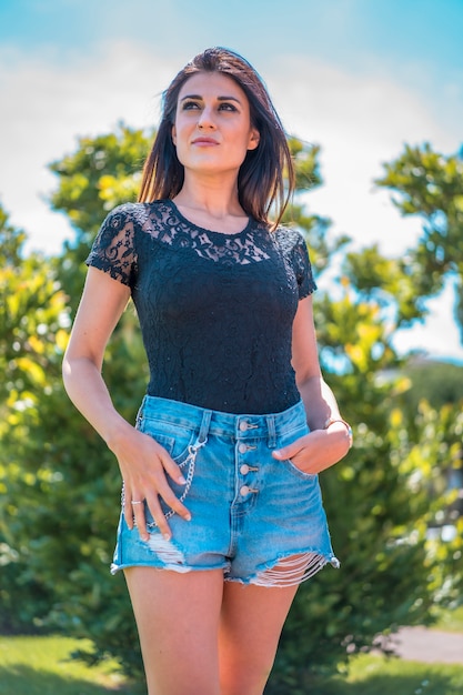 Lifestyle, portret van een ernstige jonge brunette in een zwart t-shirt en denim shorts op zoek naar links