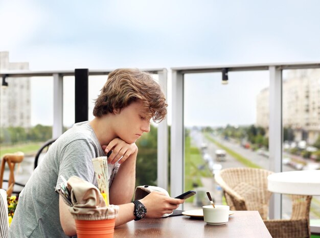 Lifestyle portret van een jonge man die buiten een smartphone gebruikt