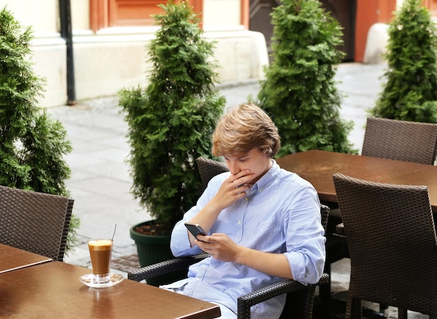 Lifestyle portret van een jonge man die buitenshuis een smartphone gebruikt