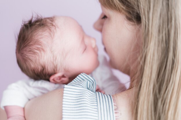 Lifestyle portret van een jonge moeder en haar pasgeboren, drie weken oude dochter.