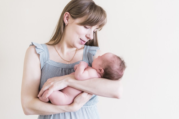 Lifestyle portret van een jonge moeder en haar pasgeboren, drie weken oude dochter.