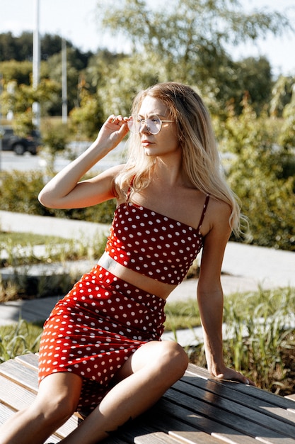 Lifestyle portret van een jonge vrouw buiten in de stad, gekleed in een rode outfit: rok en top.