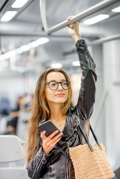 Lifestyle-portret van een jonge zakenvrouw die met een smartphone in de moderne trein staat